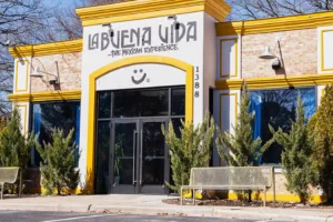 A mexican restaurant, La Buena Vida, hau0219 had commercial glass doors installed. Its outside is white and light colored brick with bright yellow trim.