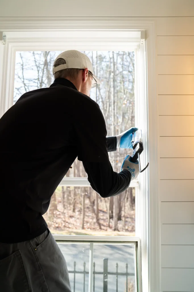 A man works on a window seal to repair it