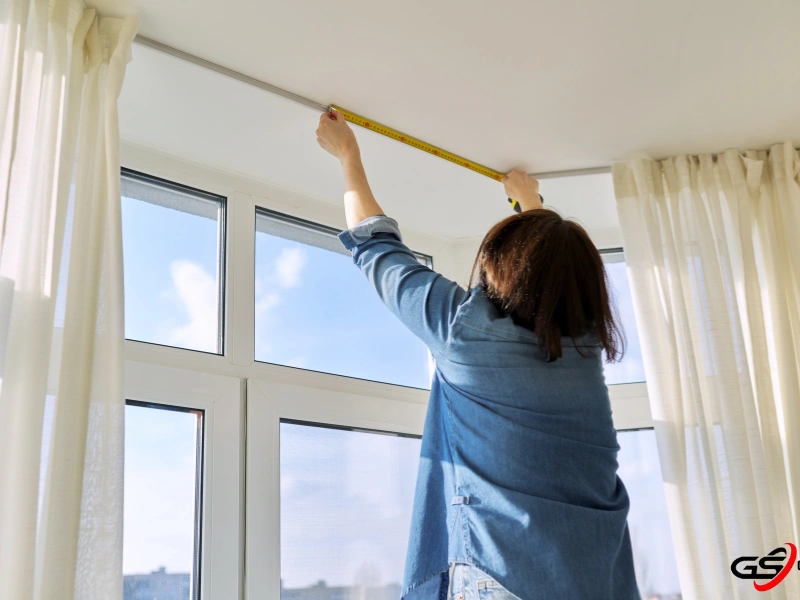 A woman measure the ceiling to determine the proper measurement for triple pane windows. 