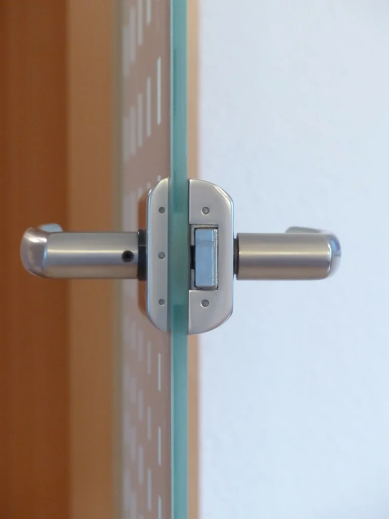 Close-up of a metal hinge mounted on a frameless glass shower door, highlighting professional glass shower door installation details in Wake Forest